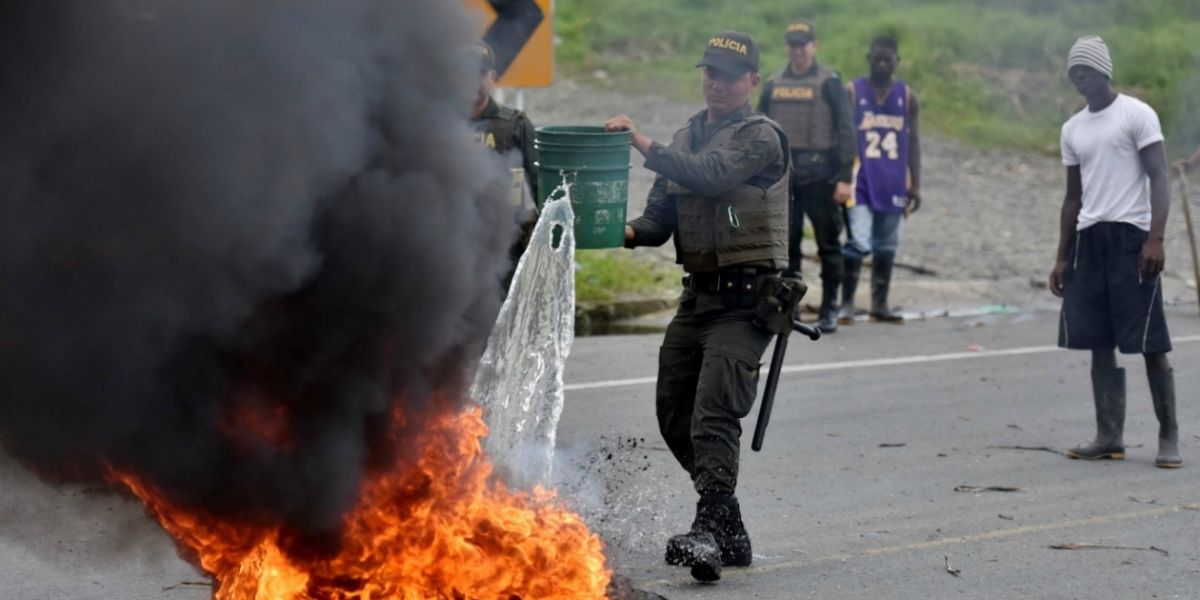 Miembros de la policía apagan una barricada en llamas durante una protesta el 3 de junio de 2017, en Buenaventura.