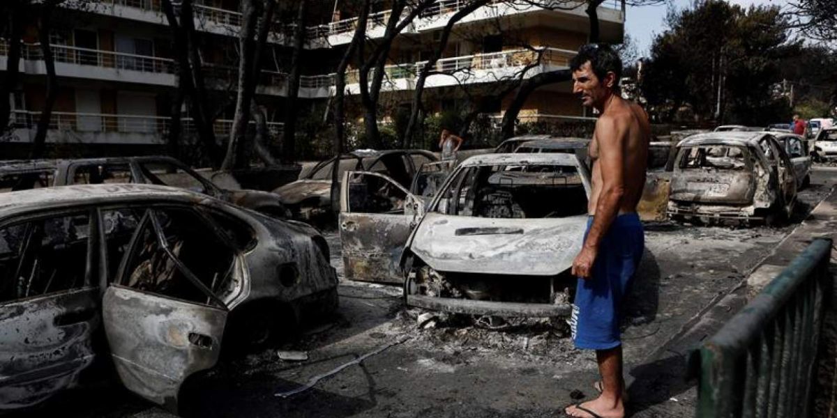 EFE. Un residente observa el estado en que han quedado varios coches calcinados tras el paso de las llamas por Mati, barrio del noreste de Atenas (Grecia) .