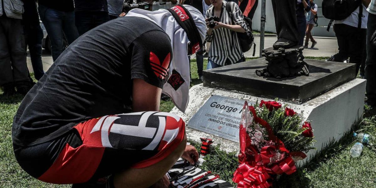 Un hombre pone flores en homenaje a las víctimas del incendio registrado en la madrugada de este viernes, en el centro de entrenamiento del club de fútbol Flamengo.