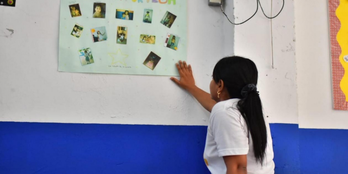 La profesora Shirley Pardo observa la cartelera de reconocimiento a María José.