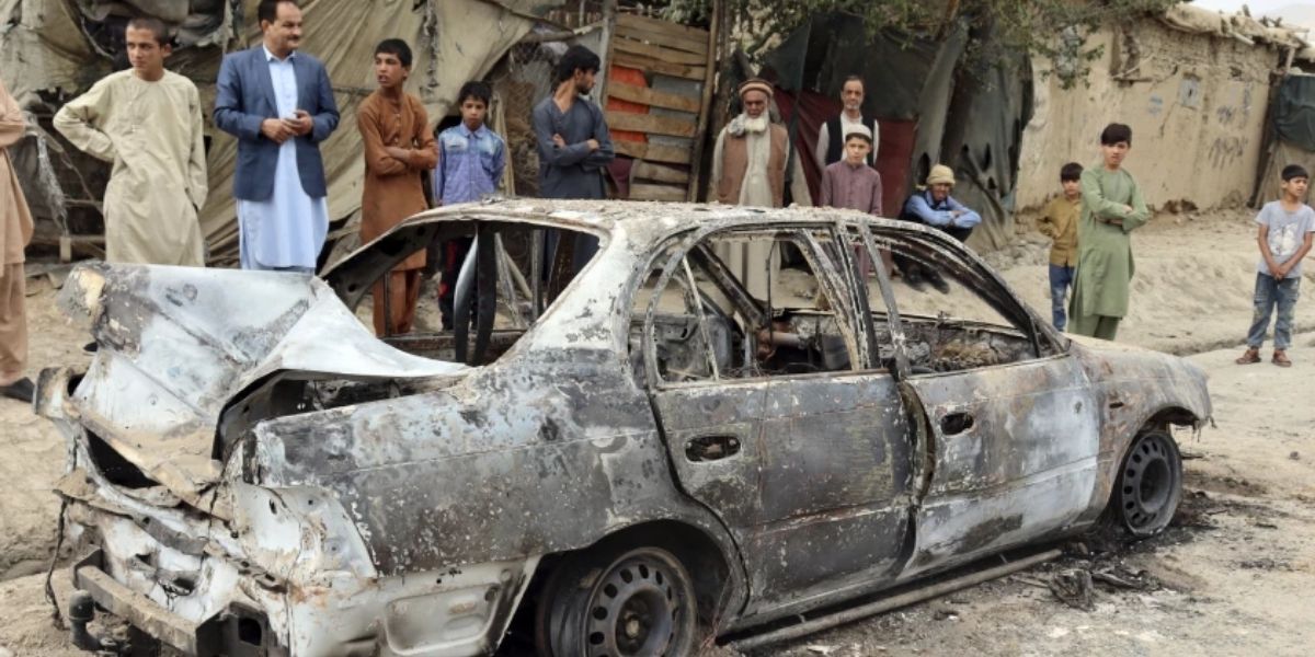 Personas mirando un vehículo dañado por un ataque con un cohete en Kabul, 