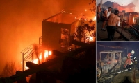  Varias personas intentan sofocar las llamas en sus viviendas que se han visto afectadas por un incendio forestal que alcanzó ayer en Valparaíso.