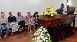 Féretro donde se encontraba el cuerpo de Rafael Viloria. Su hermano Zacarías llora mientras lo observa.
