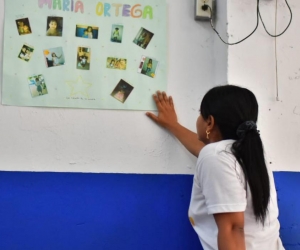 La profesora Shirley Pardo observa la cartelera de reconocimiento a María José.