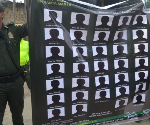 Policía muestra cartel de los 29 más buscados. 