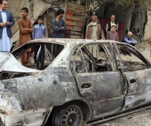 Personas mirando un vehículo dañado por un ataque con un cohete en Kabul, 