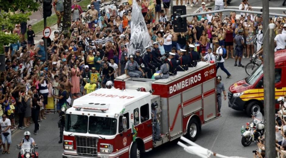 Decenas de personas sigue el camión de bomberos con los restos del astro de Brasil.